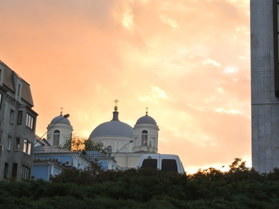 edificio e igreja, céu laranja ao fundo